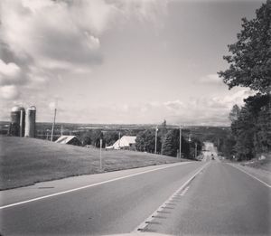 Road leading towards city against sky