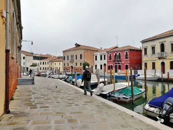 People on street amidst buildings in city against sky