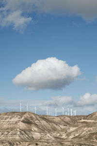 Wind turbines on mountains against cloudy sky