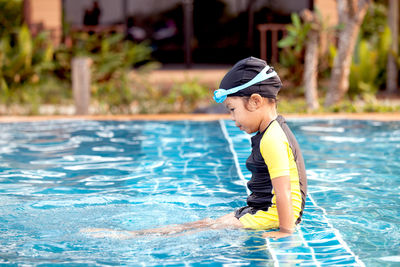 Side view of girl sitting in swimming pool