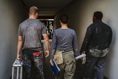 Rear view of construction manager and workers walking towards gate