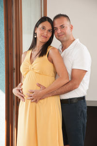 Portrait of man standing with pregnant girlfriend at home