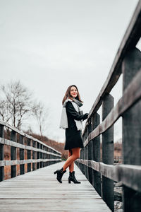 Side view of woman standing on footbridge