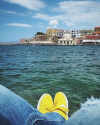 Low section of man by water against sky