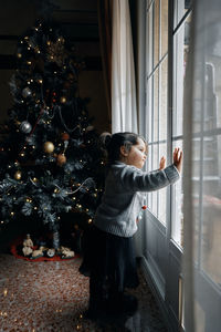 Full length of girl standing in christmas tree