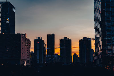 Modern buildings in city against sky during sunset