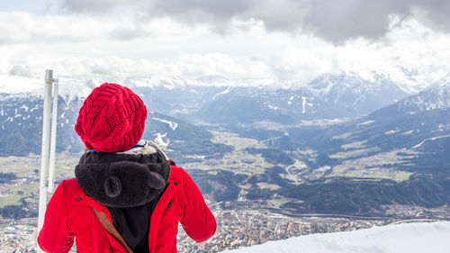 Rear view of woman standing against snowcapped mountains