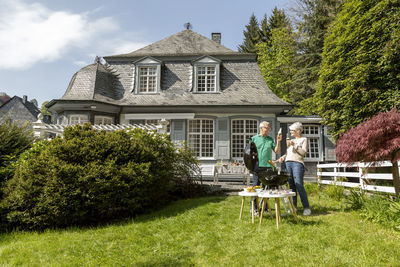 Happy senior couple having a barbecue in garden of their home