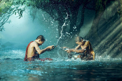 Monks splashing water in river