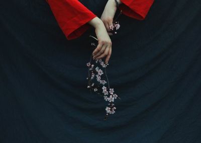 Low section of woman holding umbrella over black background