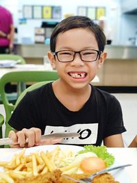 Portrait of happy boy having food at table in restaurant