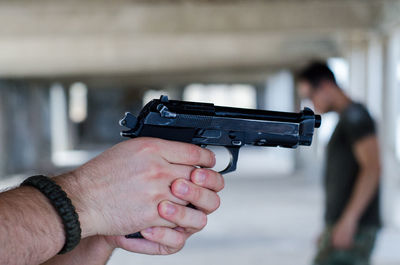 Cropped hands holding gun by man