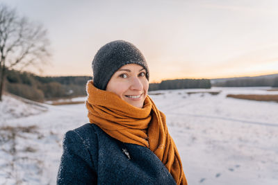 Portrait of a young woman in winter clothes and a hat wrapped in a scarf with a big smile