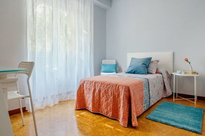 Interior of cozy single bedroom decorated with quilt and curtains