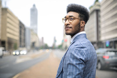 Portrait of young man standing against city