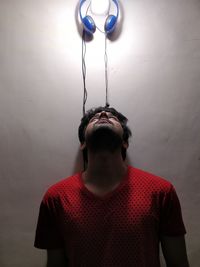 Man standing below headphones hanging on white wall