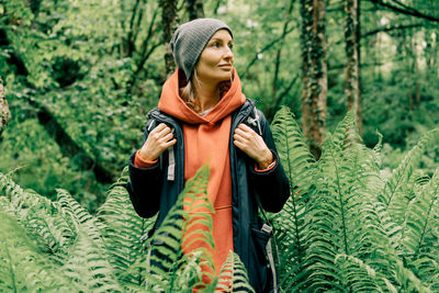 Young caucasian woman in a raincoat and a hat in the thickets of the forest