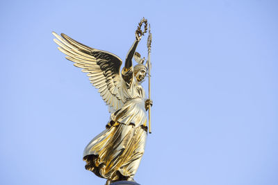 Low angle view of angel statue against clear blue sky