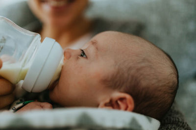 Close-up of mother feeding baby boy while sitting at home