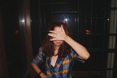 Woman covering face while standing in darkroom