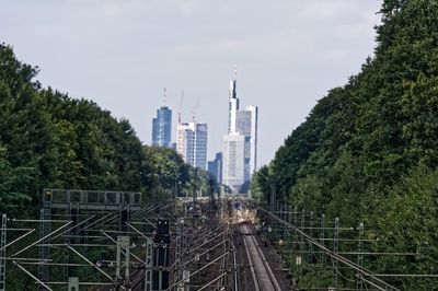Railroad tracks amidst trees and buildings against sky