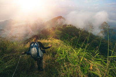 Rear view of female hiker walking on grassy mountain