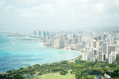 Cityscape by sea against sky