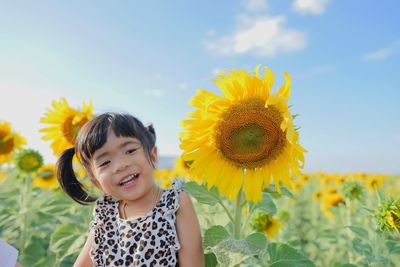 Smiling girl standing by sunflowers