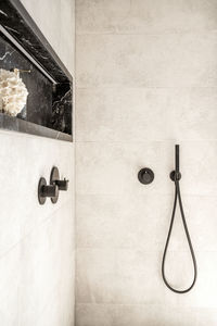 Interior of bathroom with shower cabin with black faucet handles and hose on white walls