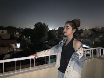 Young woman standing against built structures against sky