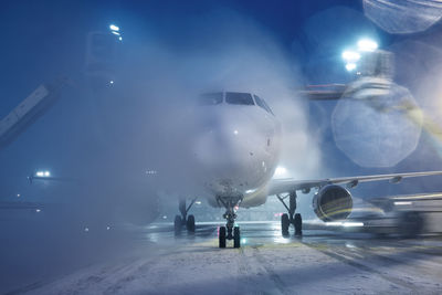 Deicing of airplane before flight. winter frosty night and ground service at airport.