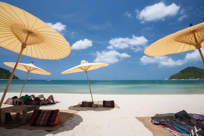 Deck chairs and parasols on beach against sky