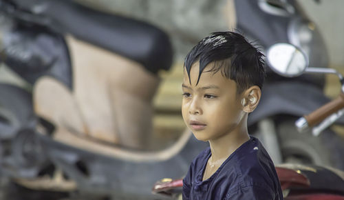 Boy looking away against motor scooters