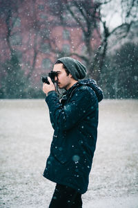 Side view of person photographing on snow