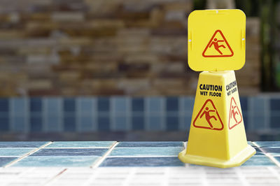 Close-up of yellow sign by swimming pool