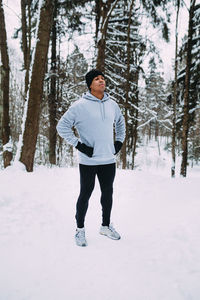 Full length of young man standing on snow covered field