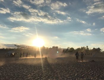 People on beach against sky during sunset