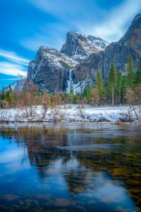 Scenic view of lake by snowcapped mountains against sky