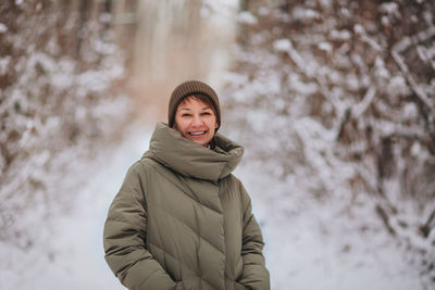 Portrait of smiling young woman standing in snow