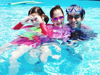 Portrait of mother and children enjoying in swimming pool