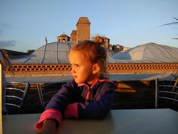 Portrait of happy girl sitting against sky