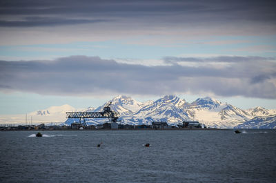 Scenic view of sea by snowcapped mountains against sky