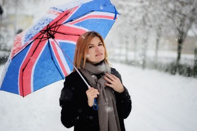 Portrait of woman with umbrella standing in snow