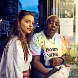 Portrait of friends standing on street in city