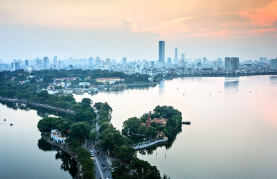 River amidst buildings in city against sky during sunset