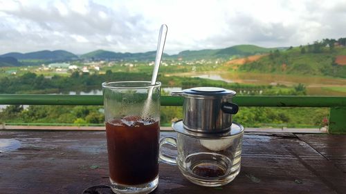 Close-up of drink on table against mountains