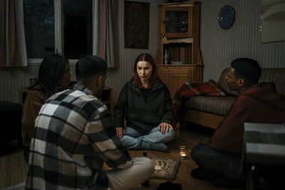 Multiracial friends with ouija board in haunted cabin