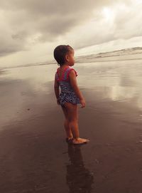 Rear view of girl standing on sand at beach