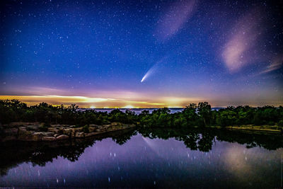 Comet neowise above the ocean horizon reflecting in the water below.