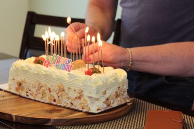 Cropped hands burning birthday candles on cake